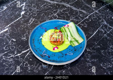 Gemüseschnitzel mit Gurkenscheiben, Blumen und Rotkohlsprossen mit grüner Sauce, zubereitet von einem hinduistischen Koch Stockfoto