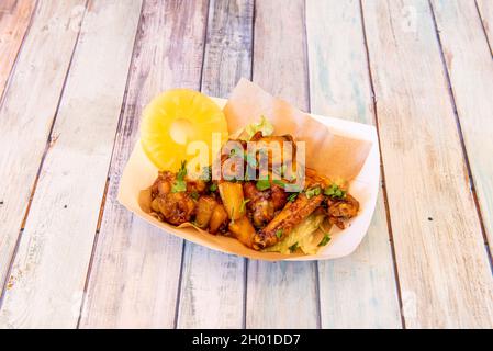 Süßes Chili Chicken Wings Schmorgericht mit Ananas und frischer Petersilie auf Pappkarton zum Mitnehmen Stockfoto