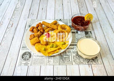 Tex-Mex-Vorspeiseteller mit Chicken Wings, Zwiebelringen, Guacamole Tortilla-Chips, Nuggets und Käsestäbchen mit Saucen Stockfoto