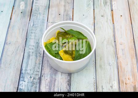 Schüssel mit fleischgefüllten Ravioli mit Ricotta, Basilikumblättern und Pesto-Sauce mitnehmen Stockfoto