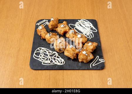 Seehechtbonbons mit Mehl und Ei in Olivenöl mit Mayonnaise-Sauce und Mohn gebraten zerschlagen Stockfoto