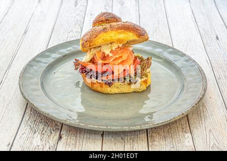 Brioche-Brot-Sandwich mit geräuchertem Lachs, Tomatenscheiben, Eichensalat mit frischem Käse und Orangano Stockfoto