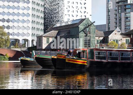 Ein Mann, der Wartungsarbeiten an seinem Schmalboot am Kanalbecken der Gas Street in Birmingham, Großbritannien, durchführt Stockfoto