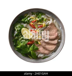 Pho Bo Suppe mit Rindfleisch, Reisnudeln, Limette, Chilischote in einer grauen Schüssel, isoliert auf weißem Hintergrund. Vietnamesische Küche. Stockfoto