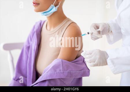 Junge Patientin erhält Impfung gegen Coronavirus, während COVID-19 Pandemie, Krankenschwester Injektion in die Schulter, Ernte. Medic immunisiert Weibchen Stockfoto