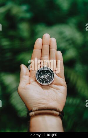 Hand mit Kompass gegen tropischen Wald Dschungel Gelände. POV Reisekonzept Stockfoto