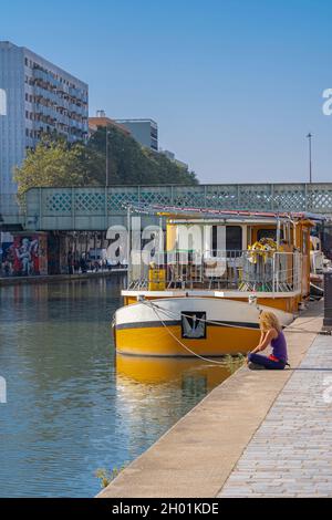 Paris, Frankreich - 10 09 2021: Ourcq-Kanal. Frau, die auf dem Dock in der Nähe der Ardennen-Fußgängerbrücke sitzt Stockfoto