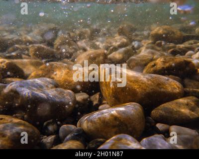 Kieselsteine steinigen unter der Wasseroberfläche in der Nähe des Seeufers, natürliche Szene, Nahaufnahme Stockfoto