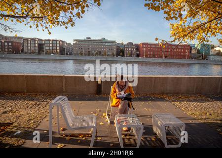 Moskau, Russland. 10. Oktober 2021 An einem sonnigen Herbsttag in Moskau, Russland, Liest Eine Frau ein Buch über den Krim-Damm im Muzeon-Park Stockfoto