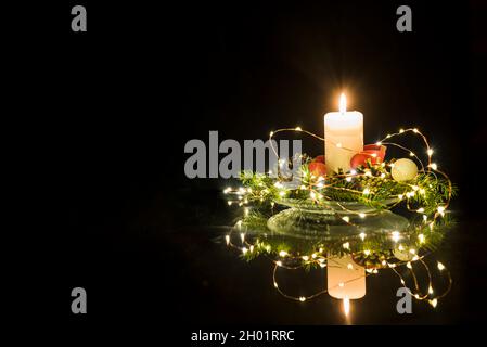 Weihnachtliche Blumendekoration mit Kerze und dunklem Hintergrund. Stockfoto