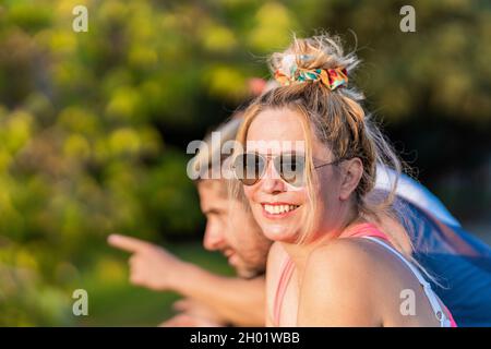 Frau mit Sonnenbrille lächelt neben Freunden Stockfoto