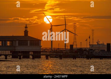 Windturbinen auf Tilbury docken bei Sonnenuntergang von der Gravesend Promenade aus an. Reflektiert auf der Themse. Stockfoto