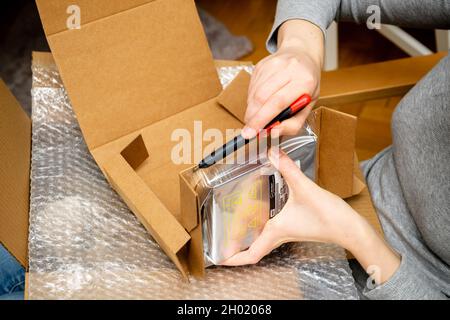 Seitenansicht der Frau Hand Auspacken Western Digital HDD Festplatte in Kunststoff Luftpolsterfolie Stockfoto