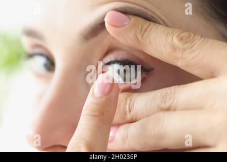 Frau zieht aus der Nähe eine weiche Kontaktlinse über die Augen Stockfoto