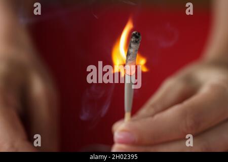 Brennendes Match in der Hand auf rotem Hintergrund Stockfoto