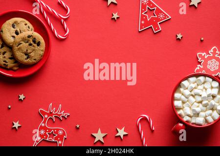 Leckere hausgemachte Weihnachtsplätzchen, heißer Kakao mit Salmmilana, Dekorationen auf rotem Hintergrund. Flach liegend, Draufsicht, Overhead. Stockfoto
