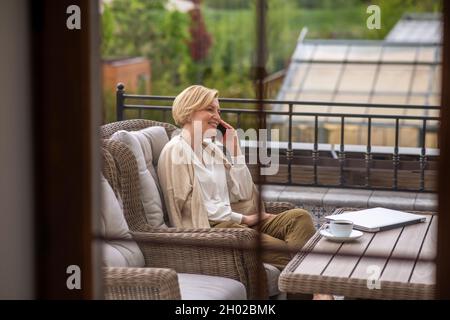 Eine Dame mittleren Alters, die im Freien auf dem Smartphone spricht Stockfoto