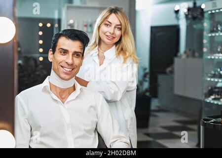 Weibliche Friseur wickeln Papier Kragen um Client Hals Stockfoto