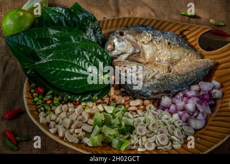 Traditionelle thailändische Essen: Gebratene Makrele serviert mit frischem Gemüse und Kraut, das Essen ist das thailändische Essen call Meuang Makrele (Maing-Pla-zu). Stockfoto