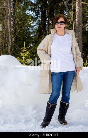Weißes Fleece-Sweatshirt mit Rundhalsausschnitt und einer Frau, die einen beigen Steppmantel und schwarze Schneestiefel trägt. Vorlage für schweres Sweatshirt Stockfoto