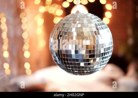 Glänzender Disco Ball in der Nähe des Nachtclubs. Glühender Ball im Zimmer, vor dem Hintergrund von Girlanden Stockfoto