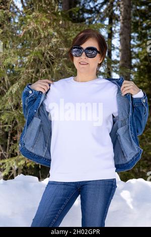 Weißes Fleece-Sweatshirt mit Rundhalsausschnitt, in dem eine Frau eine Denim-Jacke trägt. Schwere Sweatshirt Vorlage, Modell Mockup Stockfoto