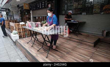 Lady Setting Display und man sitzt essen Street Food am Tisch an der Asoke Road Sukhumvit Soi 21 Bangkok Thailand Stockfoto