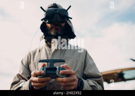 Mann, der die fpv-Quadcopter-Drohne für Luftaufnahmen und Videoaufnahmen mit einer Brillenantenne-Fernbedienung steuert. Stockfoto