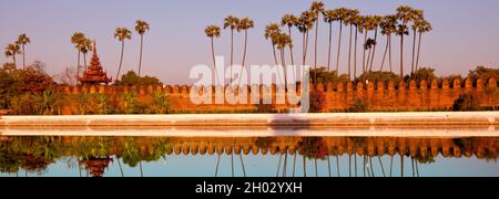 Alte braune Backstein Palastmauer mit Reflexion im Kanal rund um den Mandalay Palast in Mandalay, Burma (Myanmar) bei Sonnenaufgang Stockfoto