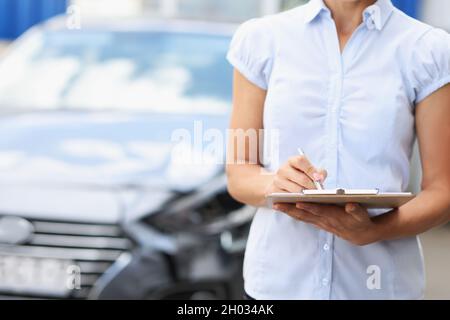 Silhouetten des Versicherungsagenten mit Klemmbrett und Stift auf dem Hintergrund eines kaputten Autos Stockfoto