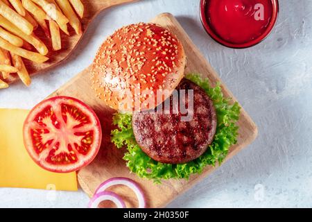 Hamburger Zutaten, von oben mit Pommes Frites und Ketchup auf einem rustikalen Holzbrett geschossen Stockfoto