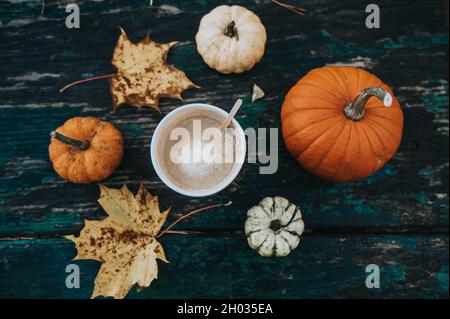 Herbst flach liegen. Kaffee in Pappbecher. Kürbisse. Ahornblätter. Alter Holztisch. Stockfoto