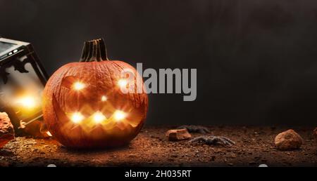 Halloween mit geschnitztem und beleuchteten Kürbis mit Spinnen und Laterne isoliert schwarzen Hintergrund. Vorderansicht. Horizontale Zusammensetzung. Stockfoto