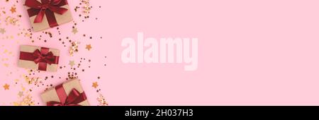 Banner mit Rahmen aus Geschenkschachteln mit roten Bändern und goldenem Konfetti auf rosa pastellfarbenem Hintergrund. Stockfoto
