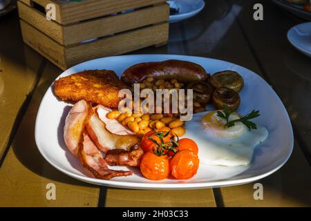 Traditionelles englisches Frühstück mit Spiegeleiern, Würstchen, Bohnen, Pilzen, gegrillten Tomaten und Speck Stockfoto