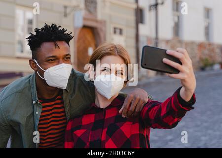Junge Biracial Paar macht Selfie für soziale Netzwerke im Freien in der Stadt, Coronavirus-Konzept. Stockfoto