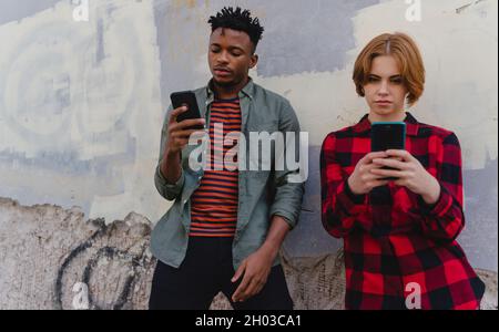 Junge Biracial Paar süchtig nach Smartphones im Freien in der Stadt, Social-Media-Konzept Stockfoto