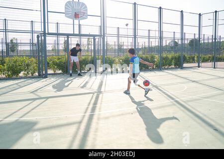 Couch, die mit einem Studenten Fußball spielt. Der Trainer ist der Torwart. Stockfoto