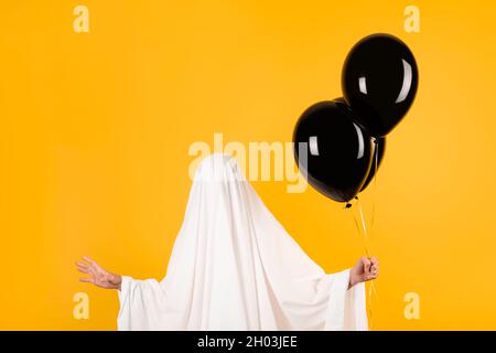 Halloween-Konzept. Mädchen in einem lustigen weißen Geister Kostüm mit schwarzen Ballons in der Hand. Stockfoto