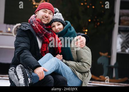 Dreißig Jahre altes Paar, das auf einer verschneiten Terasse sitzt und für ein Foto posiert. Stockfoto