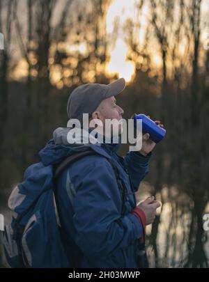 Reifer Wanderer mit Rucksack Trinkwasser aus der Flasche im Wald Stockfoto