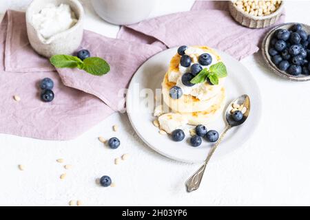 Hausgemachte Käsekuchen oder Pfannkuchen mit Heidelbeeren und Creme. Quelle für Protein, gesunde Ernährung Stockfoto