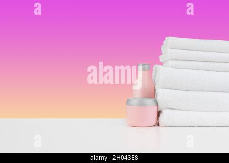 Stapel Handtücher, Flaschen mit Shampoo auf weißem Tisch Stockfoto