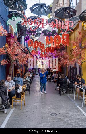 Athen Griechenland - 10.10.202: Leute, die an Halloween draußen in einem Straßencafé sitzen. Die Gasse ist komplett mit gruseligen und lustigen Ferienobjekten dekoriert. Stockfoto