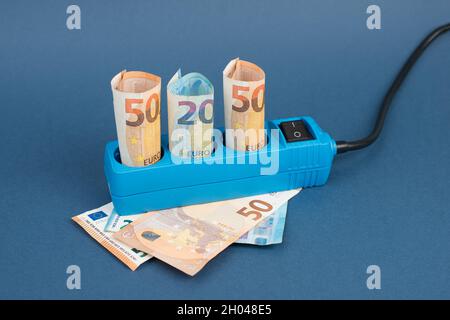 Euro-Banknoten in einer Steckdose, steigende Preise, teurer Ökostrom, Deutschland Stockfoto
