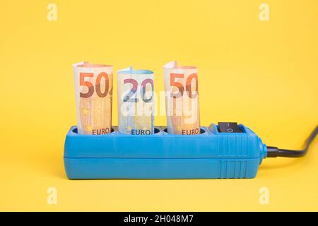 Euro-Banknoten in einer Steckdose, steigende Preise, teurer Ökostrom, Deutschland Stockfoto