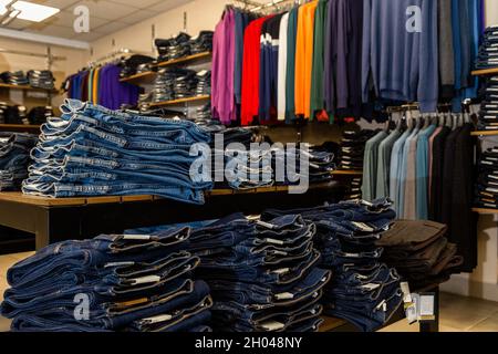 Blaue, blaue Jeans liegen gestapelt im Laden vor dem Hintergrund von Pullovern. Verkauf im Denim-Store. Stockfoto