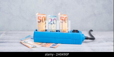 Euro-Banknoten in einer Steckdose, steigende Preise, teurer Ökostrom, Deutschland Stockfoto