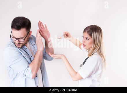 Männliche Patientin, die einen Löffel voll mit verschiedenen Pillen vom weiblichen Arzt abweist Stockfoto