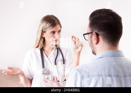 Junge Ärztin, die Pillen an männliche Patienten gibt Stockfoto